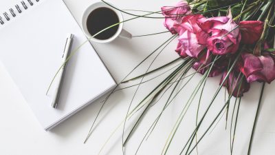 Desk with notepad, coffee, and beautiful flowers